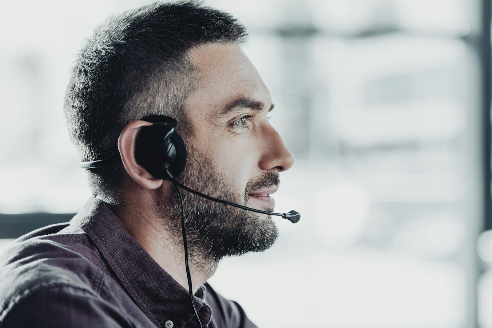 side view of handsome call center worker in headphones with microphone